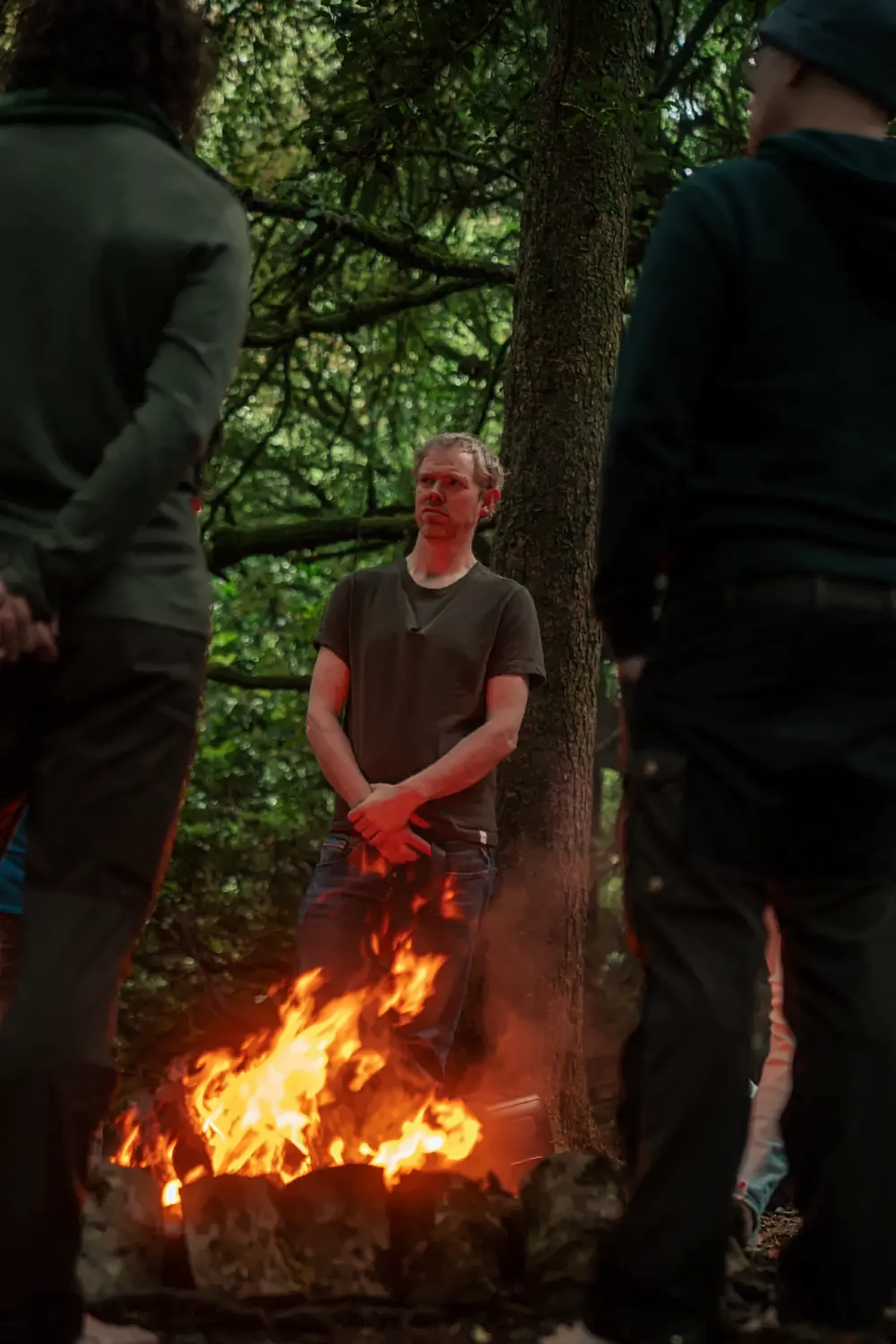 Men standing around a fire in the woods